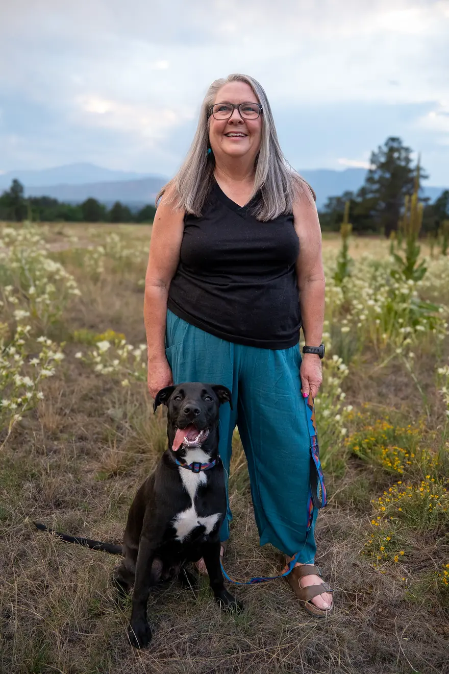 Trudy Jones standing in a Colorado meadow at dusk with her dog River
